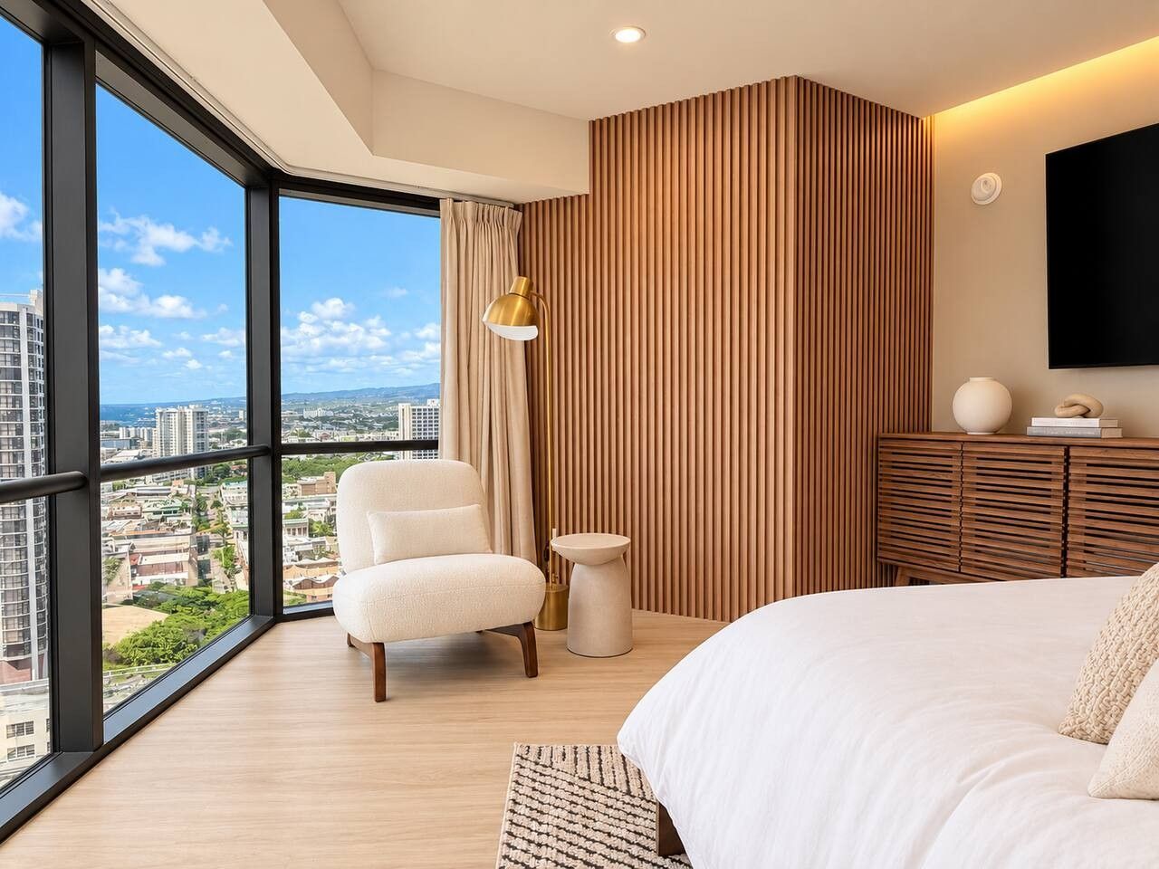 A modern hotel room with a large window, a bed, a chair, a bedside table, and a wall-mounted TV.