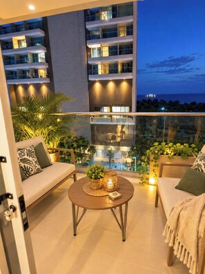 Ein Balkon mit einer Couch, einem runden Tisch und Topfpflanzen.