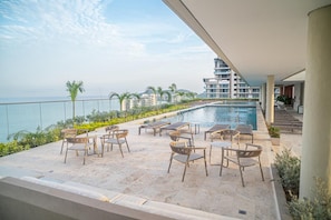 A poolside area with lounge chairs and a view of the ocean. - Stunning Oceanfront Condo in Santa Marta Sleeps 5 + Resort Amenities (BELLO HORIZONTE)