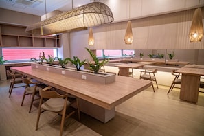 A modern interior with long wooden tables and chairs, pendant lighting, and potted plants. - Stunning Oceanfront Condo in Santa Marta Sleeps 5 + Resort Amenities (BELLO HORIZONTE)