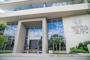 A modern building with a large glass facade, a prominent entrance, and a sign reading 'RESERVA DEL MAR.' - Stunning Oceanfront Condo in Santa Marta Sleeps 5 + Resort Amenities (BELLO HORIZONTE)