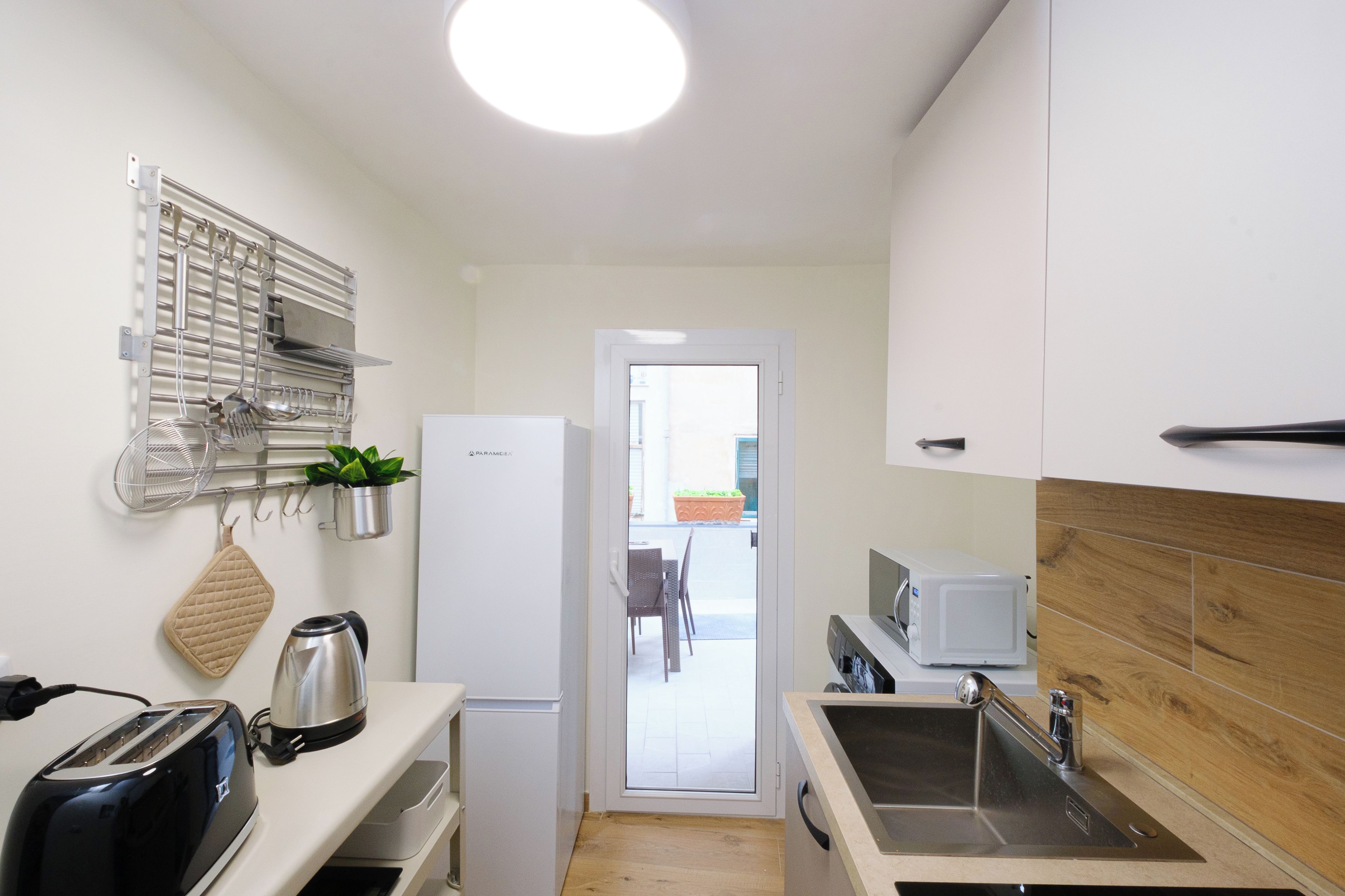 A compact kitchen with a toaster, kettle, microwave, and a sink.