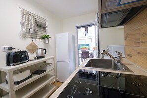 A compact kitchenette with a built-in stove, a refrigerator, and a sink. - New Listing (Napoli)