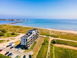 Ein modernes Gebäude mit einer Dachparkfläche und Blick aufs Meer.