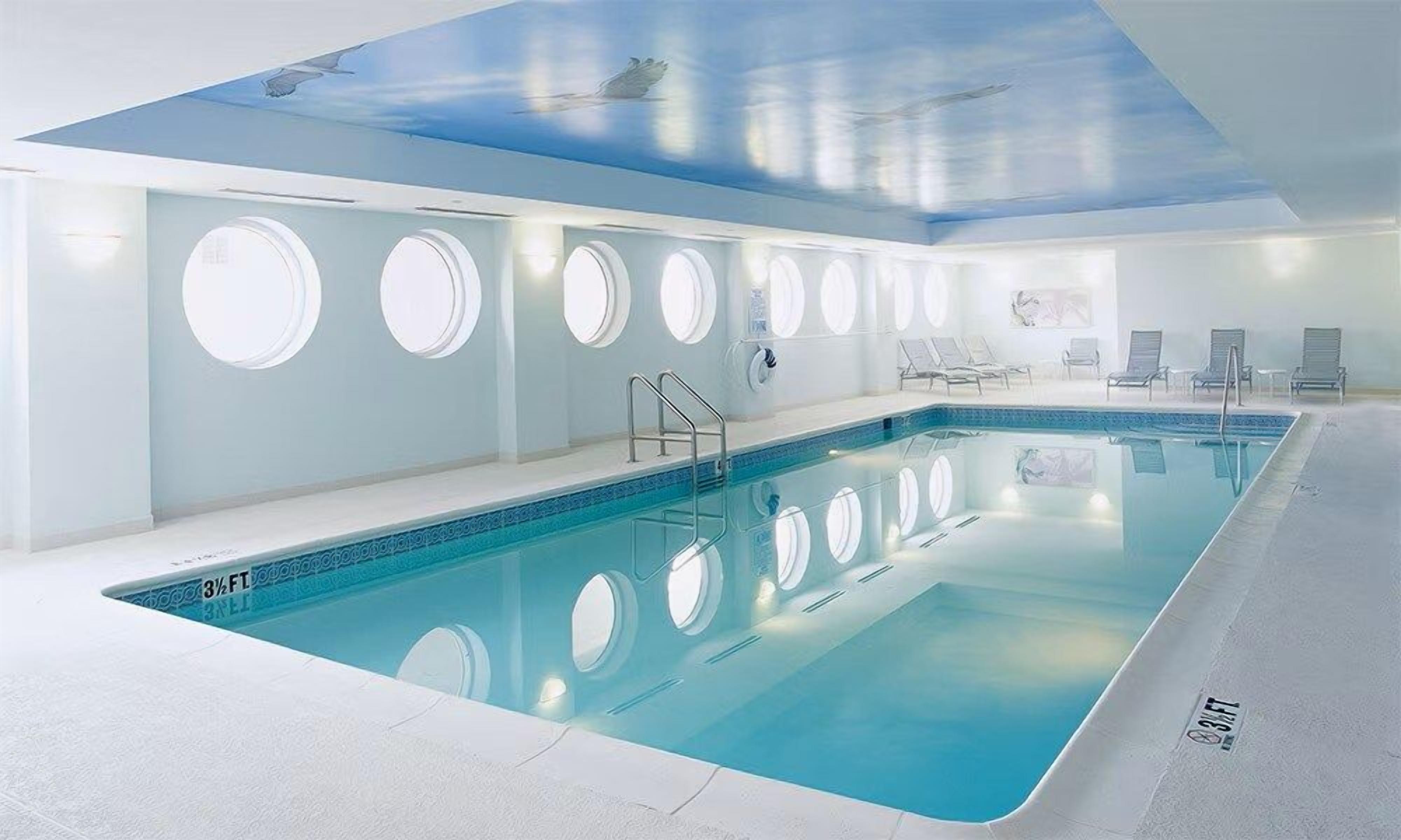A swimming pool with a 3.5 FT depth, surrounded by lounge chairs and a ceiling with circular skylights.