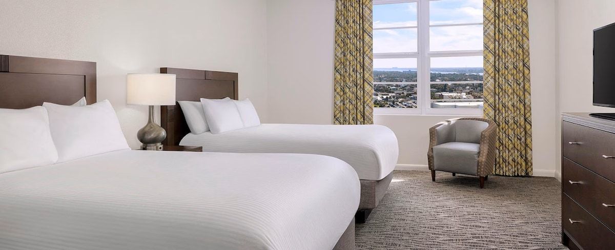 Une chambre d’hôtel avec deux lits, une chaise, une commode et un téléviseur.