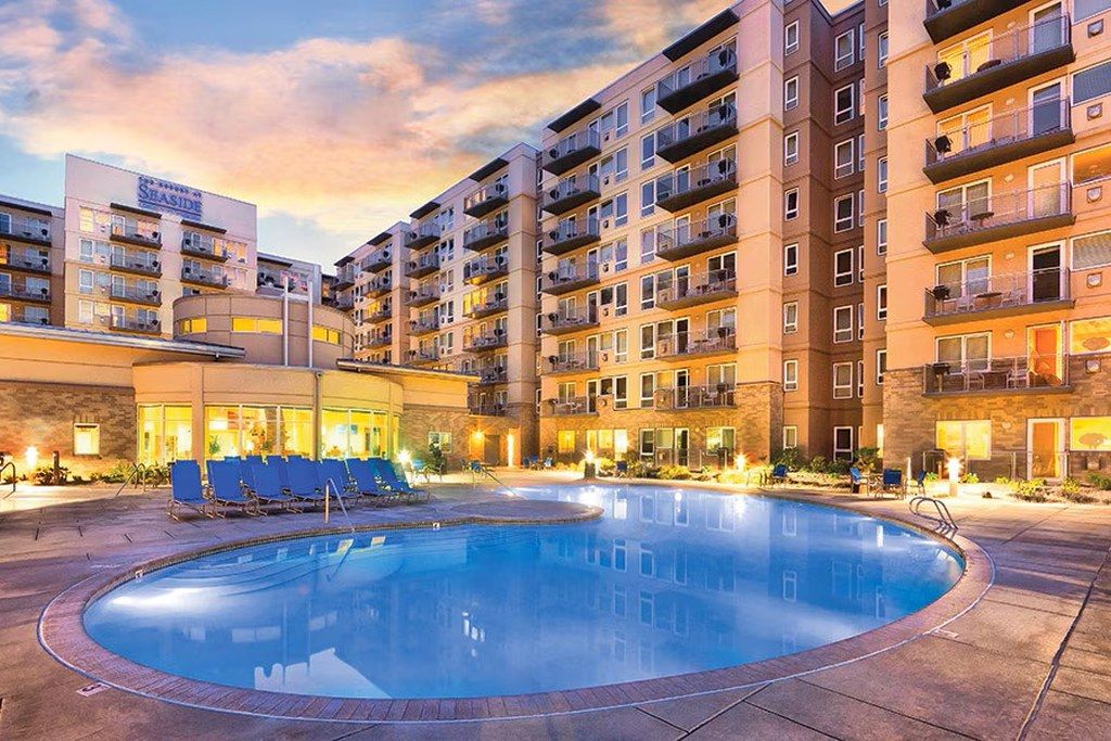 Un hôtel à plusieurs étages, doté d’une piscine et d’un espace extérieur aménagé pour s’asseoir.