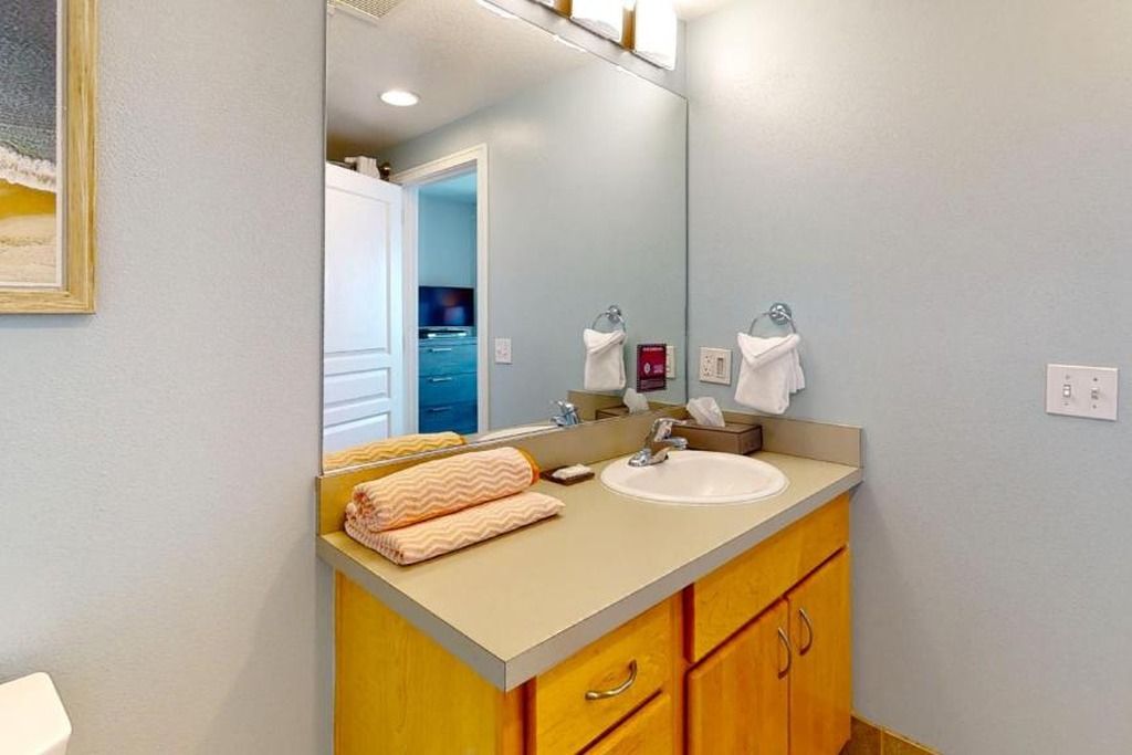 Une salle de bain avec un lavabo, un miroir et des meubles en bois.