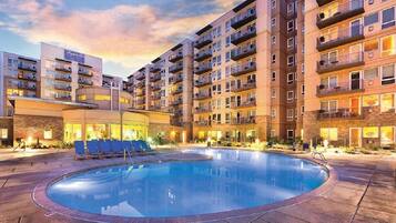 A hotel with a swimming pool, multiple balconies, and a well-lit exterior.