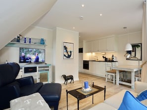 A modern living room with a television, seating, and a small dining area. - 214 - Apartment 14 "blue Anchor" (Juist)