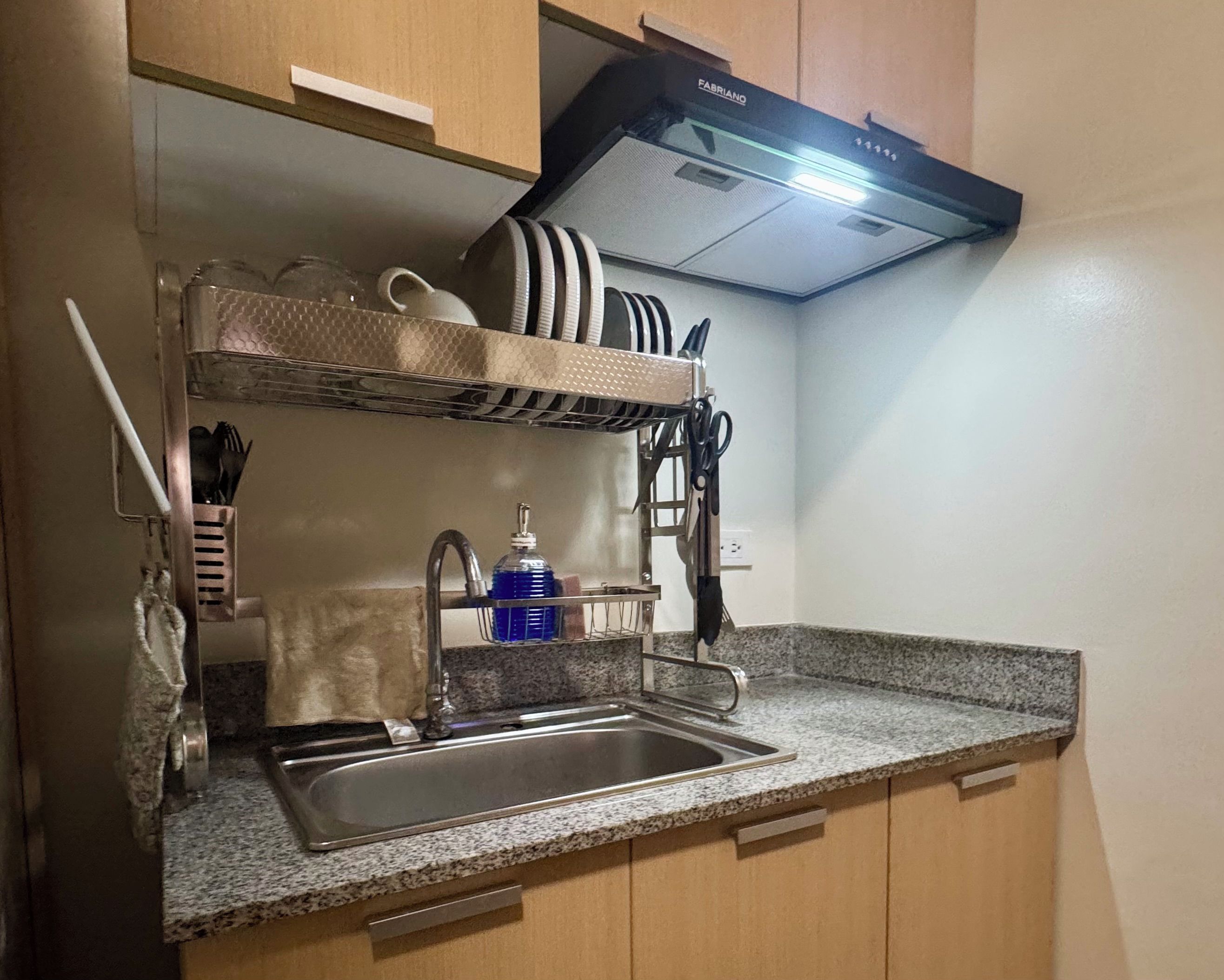 A compact kitchen with a built-in sink, a stainless steel faucet, and a dish rack.