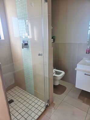 Un baño con cabina de ducha de vidrio, inodoro y lavabo.