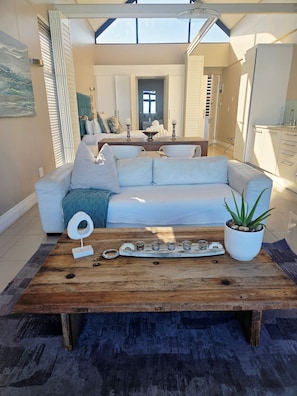 Una sala de estar moderna con un sofá blanco, una mesa de centro de madera y una planta en maceta.