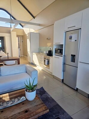 Una cocina moderna con armarios blancos, un refrigerador de acero inoxidable y un horno empotrado.