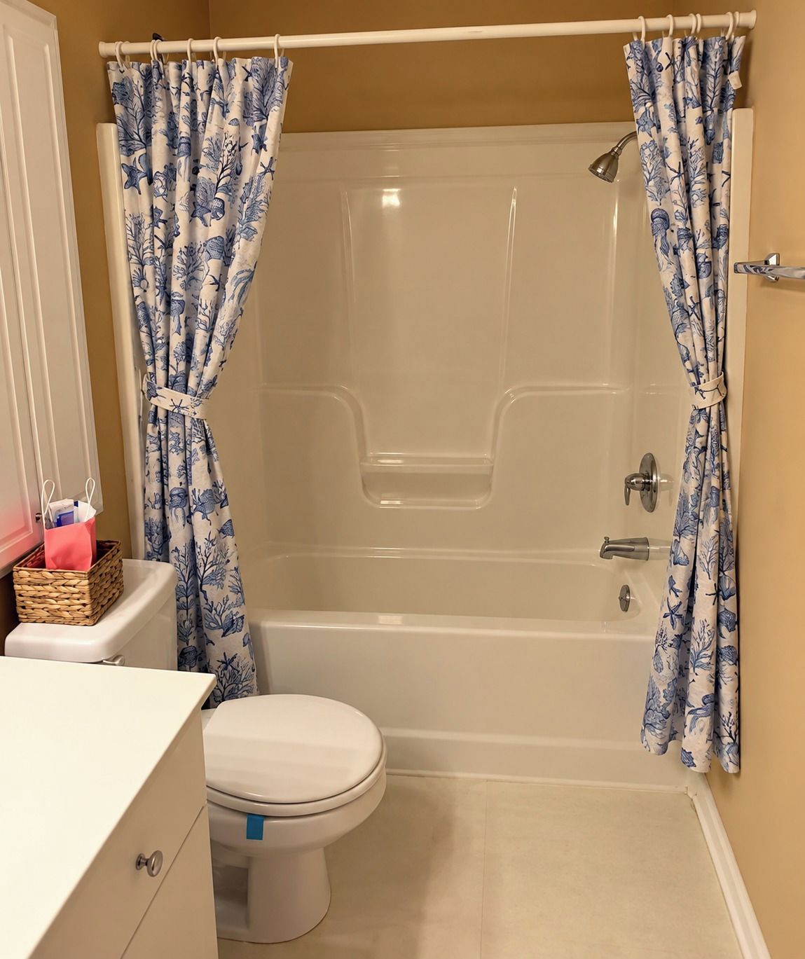 Un baño con bañera, inodoro y una cesta sobre el mostrador.