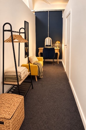 Un pasillo estrecho con una cama litera, un escritorio con silla y un espejo.