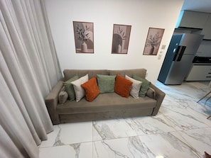 A living room with a sofa, a refrigerator, and three framed pictures on the wall. - Flats Beach (Ipojuca)