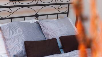 Un lit avec une tête de lit en métal, deux oreillers et une couvre-lit à motifs.
