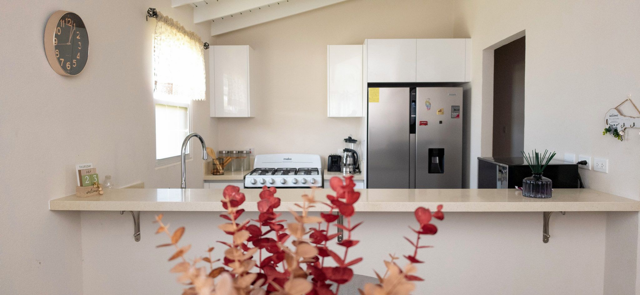 A modern kitchen with a gas stove, stainless steel refrigerator, and white cabinets.