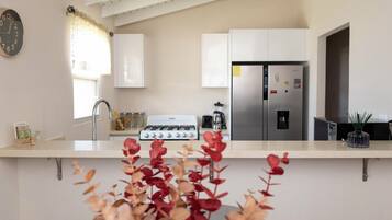 A modern kitchen with a gas stove, stainless steel refrigerator, and white cabinets.