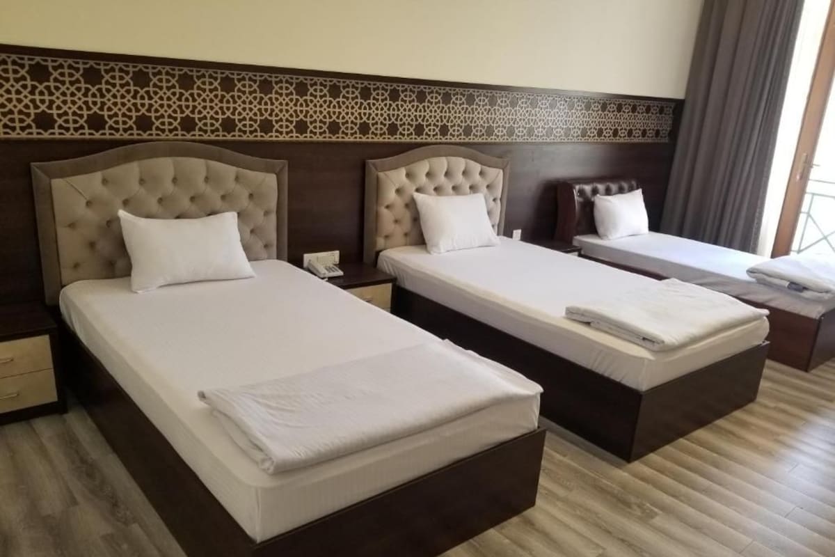 A hotel room with two beds, a nightstand, and a window with curtains.