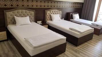 A hotel room with two beds, a nightstand, and a window with curtains.