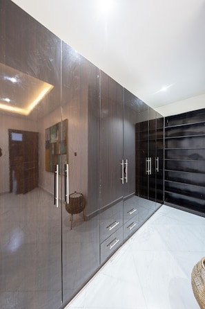 A modern interior with a large wardrobe, a small stool, and a dark sliding door. - Brickle Luxe - Modern 3BR |3.5 Baths | 24/7 Power | Lekki Phase 1 (Lekki)
