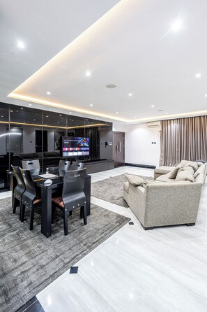 A modern living room with a dining area, a flat-screen TV, and a sofa. - Brickle Luxe - Modern 3BR |3.5 Baths | 24/7 Power | Lekki Phase 1 (Lekki)
