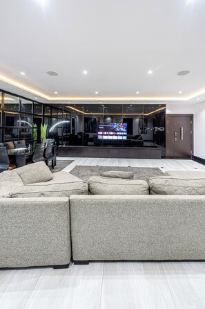 A modern living room with a sectional sofa, a flat-screen TV, and a glass partition. - Brickle Luxe - Modern 3BR |3.5 Baths | 24/7 Power | Lekki Phase 1 (Lekki)