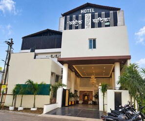 En hotelindgang med et overdækket område, en gylden statue og række af parkerede motorcykler.