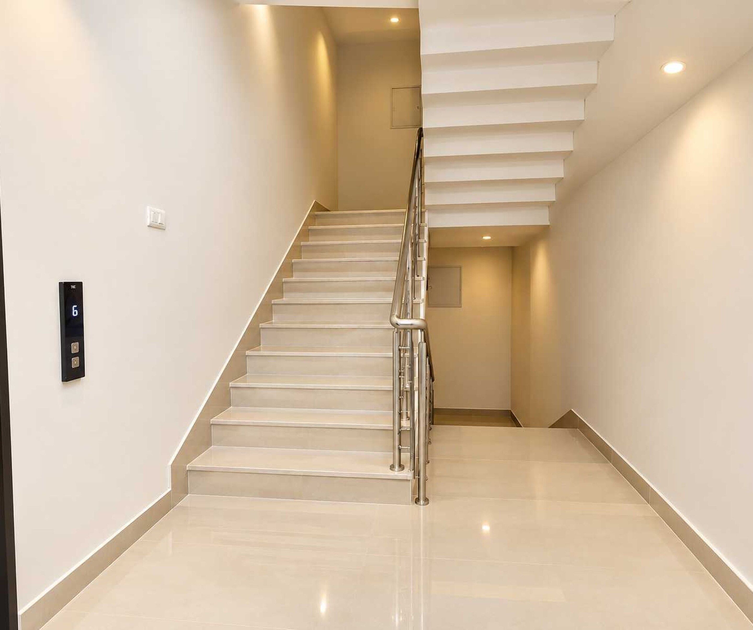 Una escalera moderna con barandilla de metal que conduce a un rellano con una puerta.