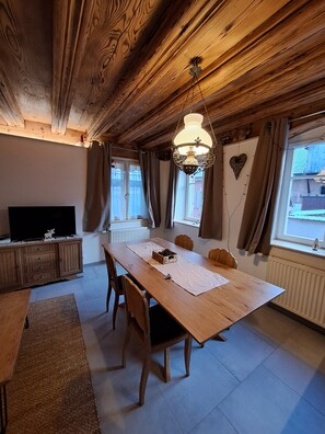 Un coin repas chaleureux avec une table en bois, des chaises et un lustre.