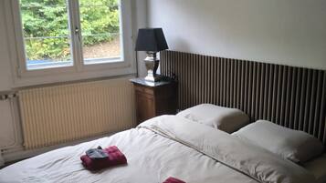 Una camera da letto con un letto, una finestra, una lampada e un termosifone.
