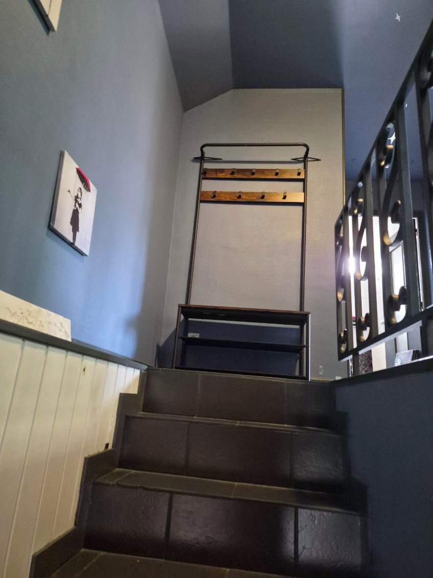 A staircase with a metal handrail and a wall-mounted rack.