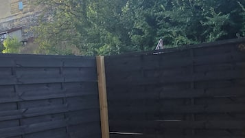 Pihalla on oleskelualue, jossa on kolme puista penkkiä ja musta aita.