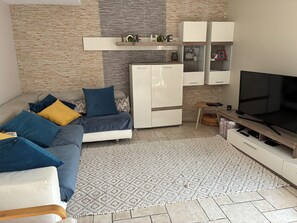 Un salon moderne comprenant un canapé, un téléviseur, un meuble et un tapis à motifs.
