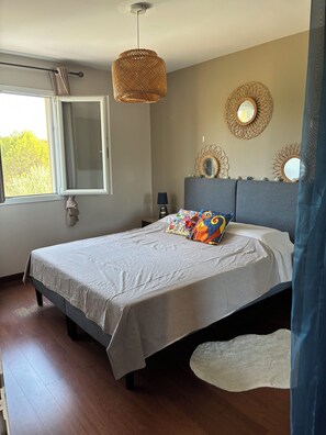 A bedroom with a bed, a hanging light fixture, a window, and wall decorations. - New Listing (34920 le cres)