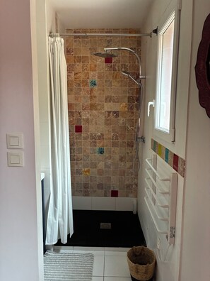 A bathroom with a shower, tiled walls, a window, and a towel rack. - New Listing (34920 le cres)
