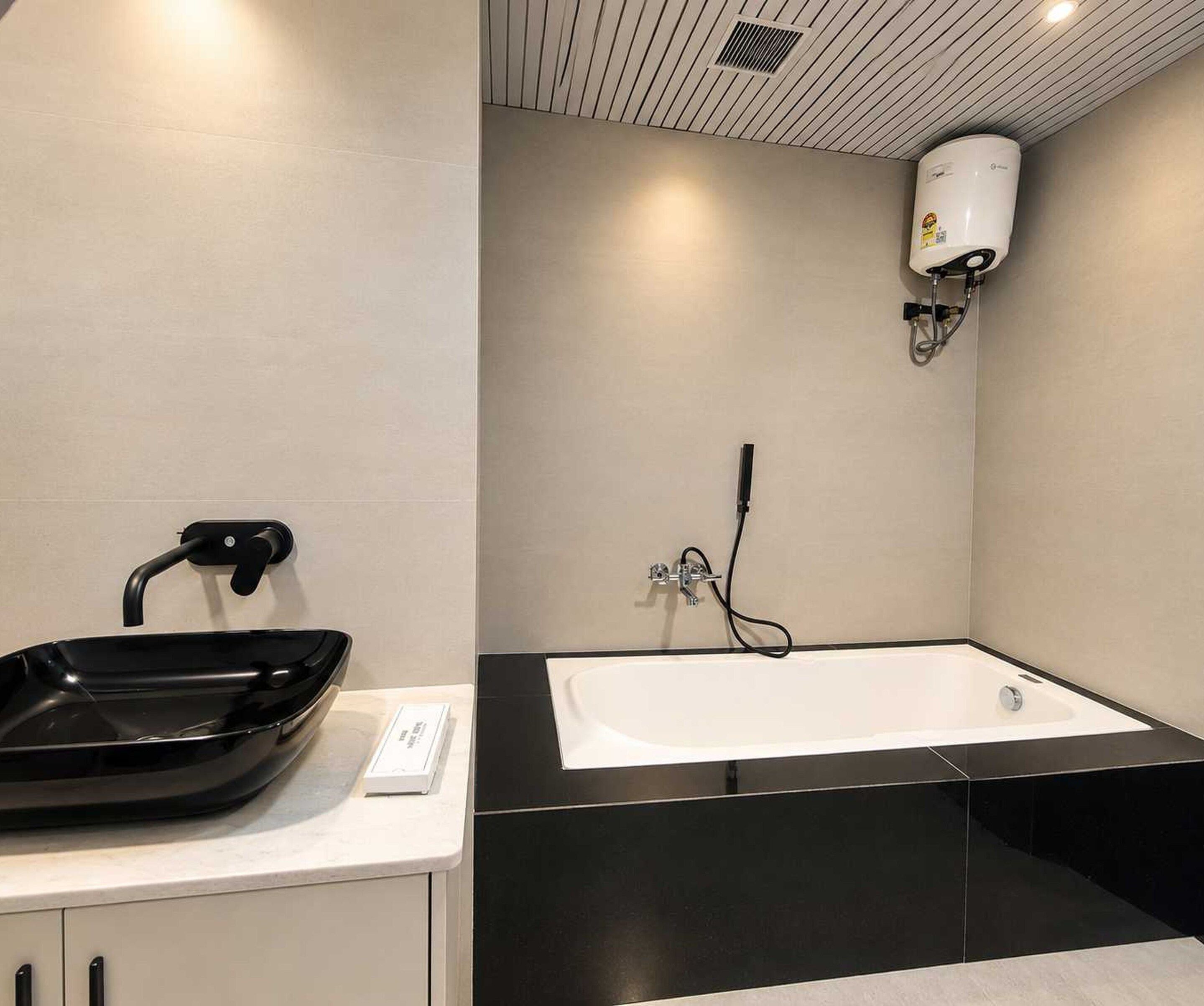 Une salle de bain moderne avec un lavabo noir, une baignoire blanche et un radiateur fixé au mur.