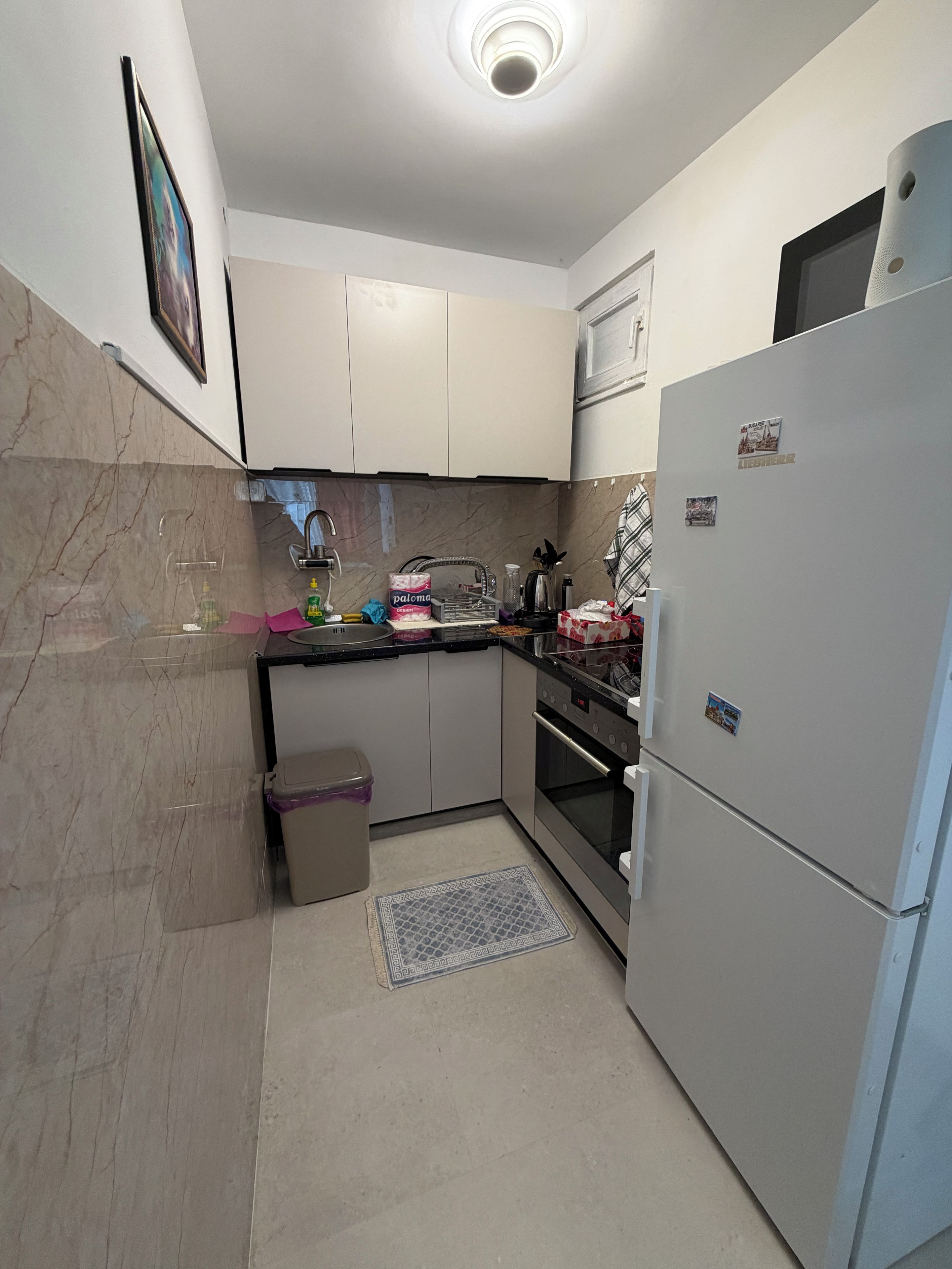 A compact kitchen with white cabinets, a stainless steel oven, and a refrigerator.