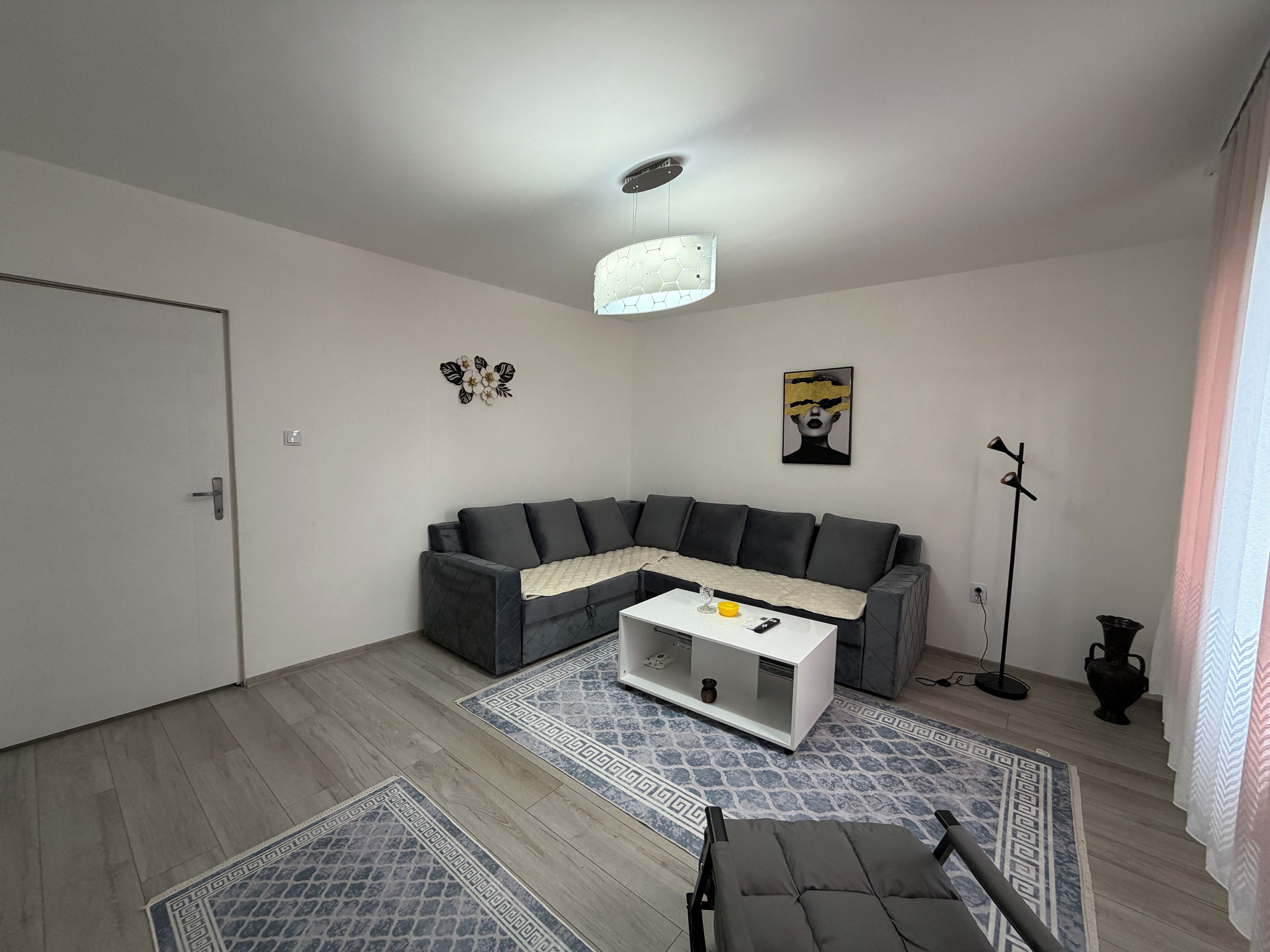 A modern living room with a sectional sofa, a coffee table, a floor lamp, and decorative wall art.