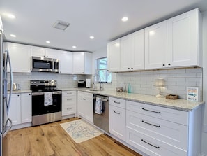 A modern kitchen with white cabinetry, stainless steel appliances, and a granite countertop. - Waterfront 2-bedroom house with direct access to the Gulf in Hudson, Fl. (Hudson)