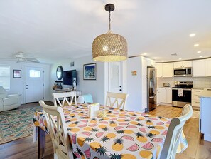 A modern kitchen with white cabinets, stainless steel appliances, and a dining area with a fruit-patterned tablecloth. - Waterfront 2-bedroom house with direct access to the Gulf in Hudson, Fl. (Hudson)