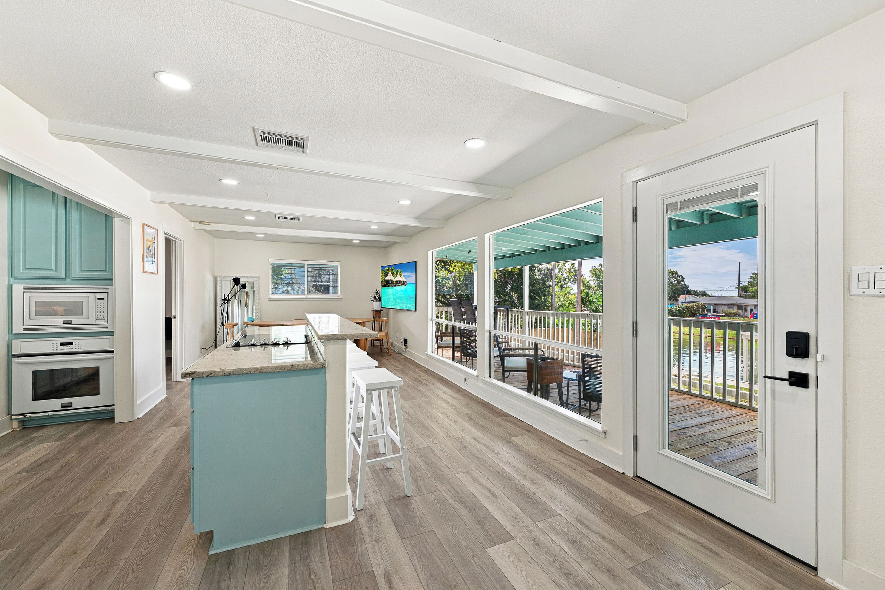 A modern kitchen with a central island, a dining area with outdoor seating, and a view of a water body.