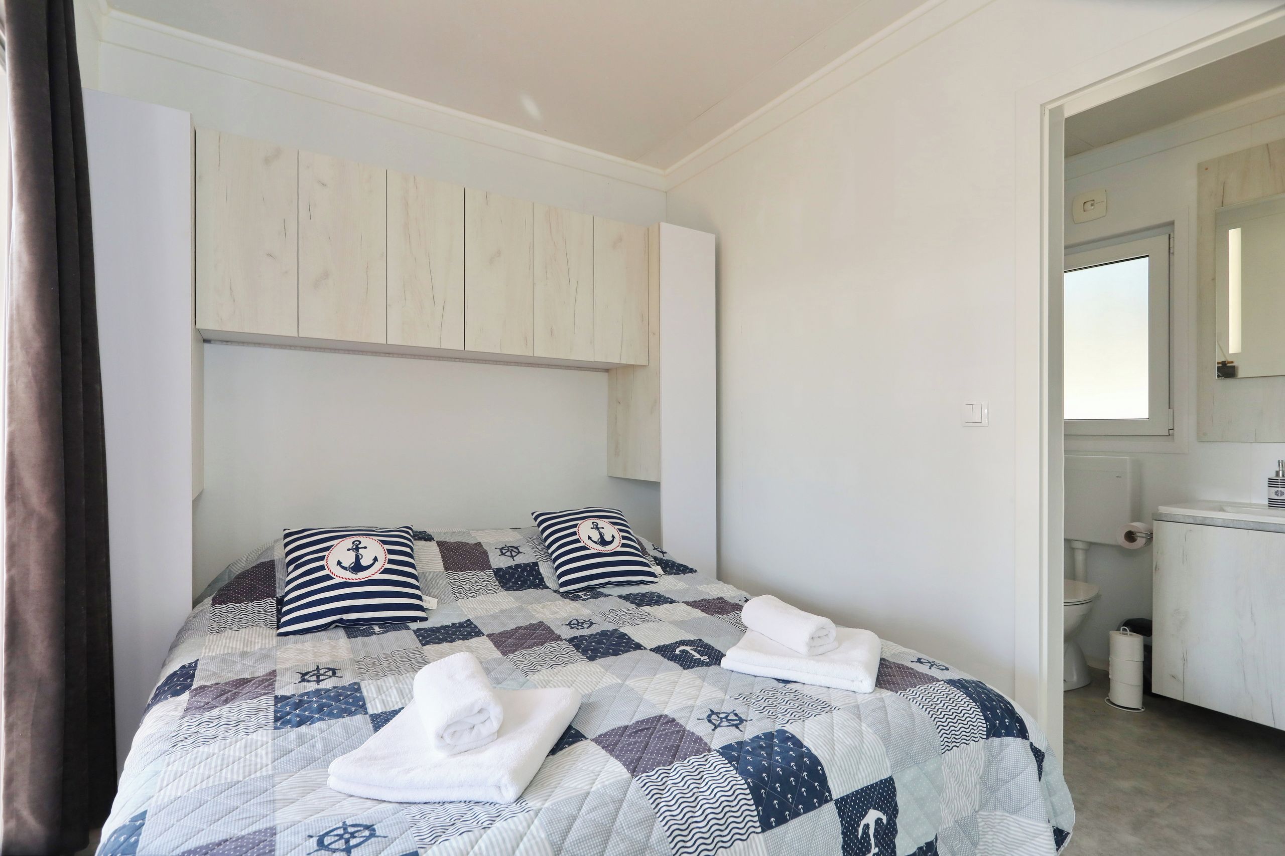Ein Schlafzimmer mit einem Bett, zwei Kissen, einer Steudecke und einem gefalteten Handtuch.