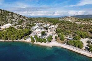 A coastal residential area with houses arranged along a beachfront, featuring clear skies and a calm sea. - Ahoi House 10 – Seaside mobile home in Drage, sleeps 4 (Drage)