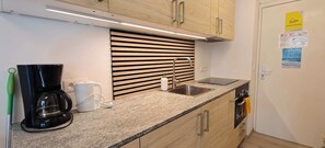 Una cocina moderna con estufa integrada, un lavamanos y una cafetera.