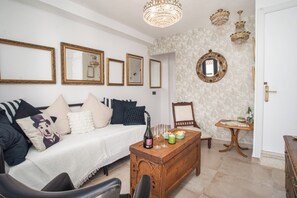 Une pièce comprenant un canapé, une table basse en bois, une chaise et une petite table sur laquelle se trouvent un vase et un livre.
