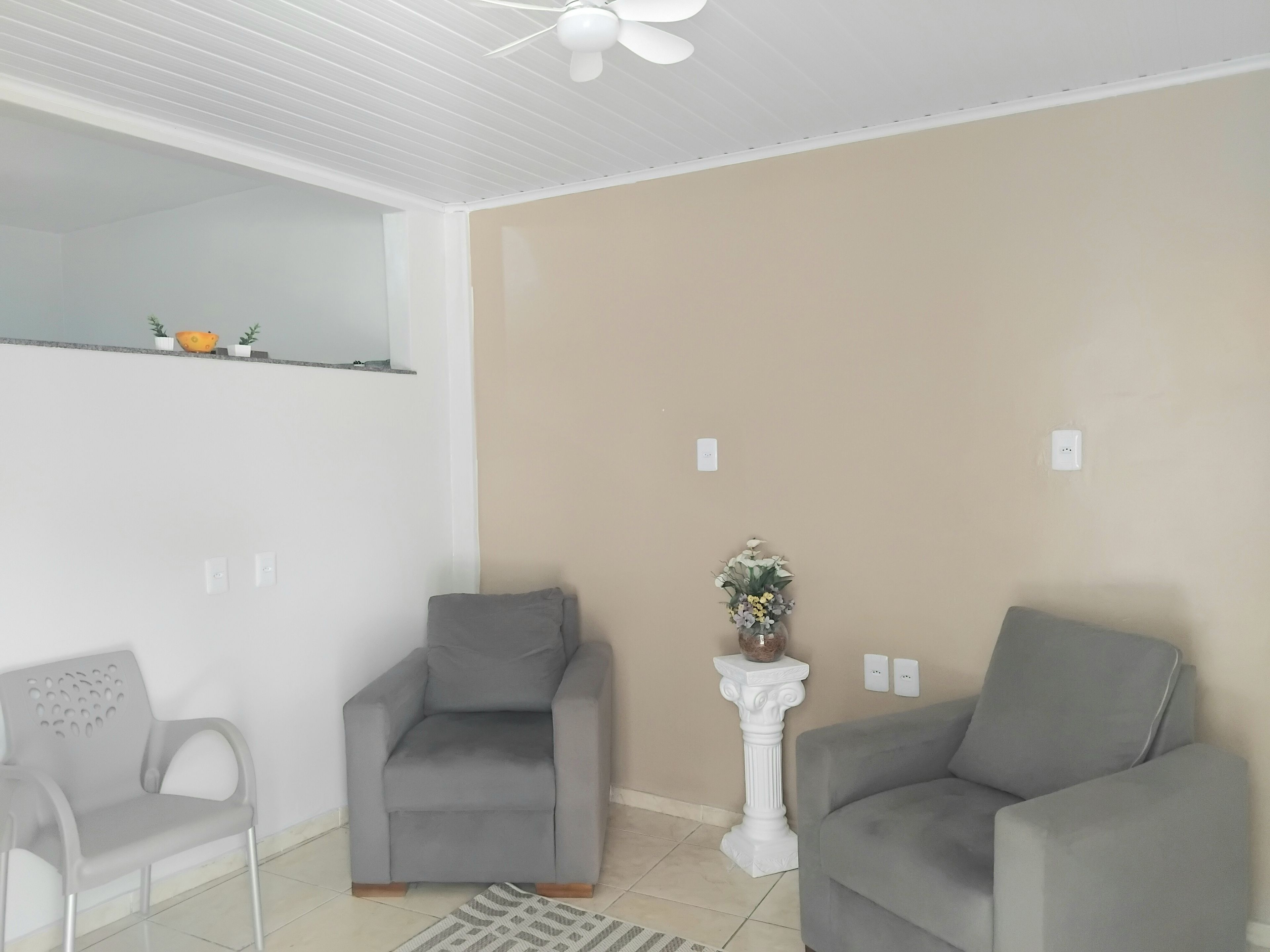 Una habitació amb dos armarions grisos, una taula auxiliar blanca amb un vas i un ventilador de sostre.