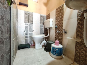 A bathroom with a toilet, a water tank, and a sink. - White Rann Homestay (Dhordo)